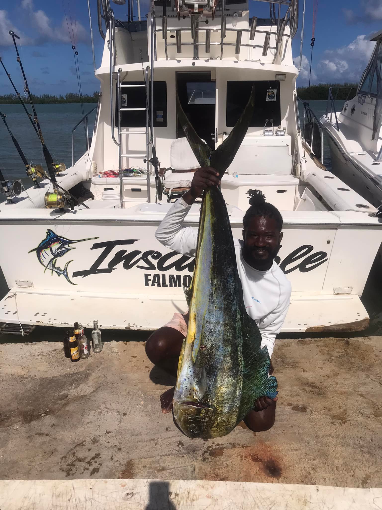 Large mahi mahi fish catch displayed on dock in Falmouth with fishing boat in background