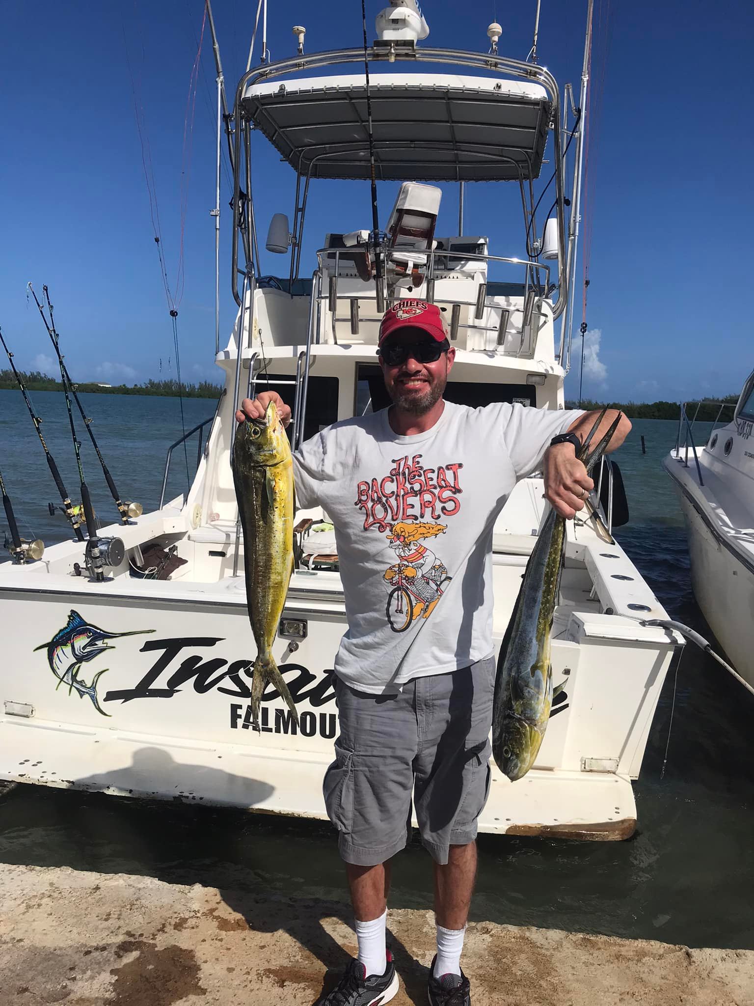 Angler displaying two mahi mahi fish on fishing boat in Falmouth waters