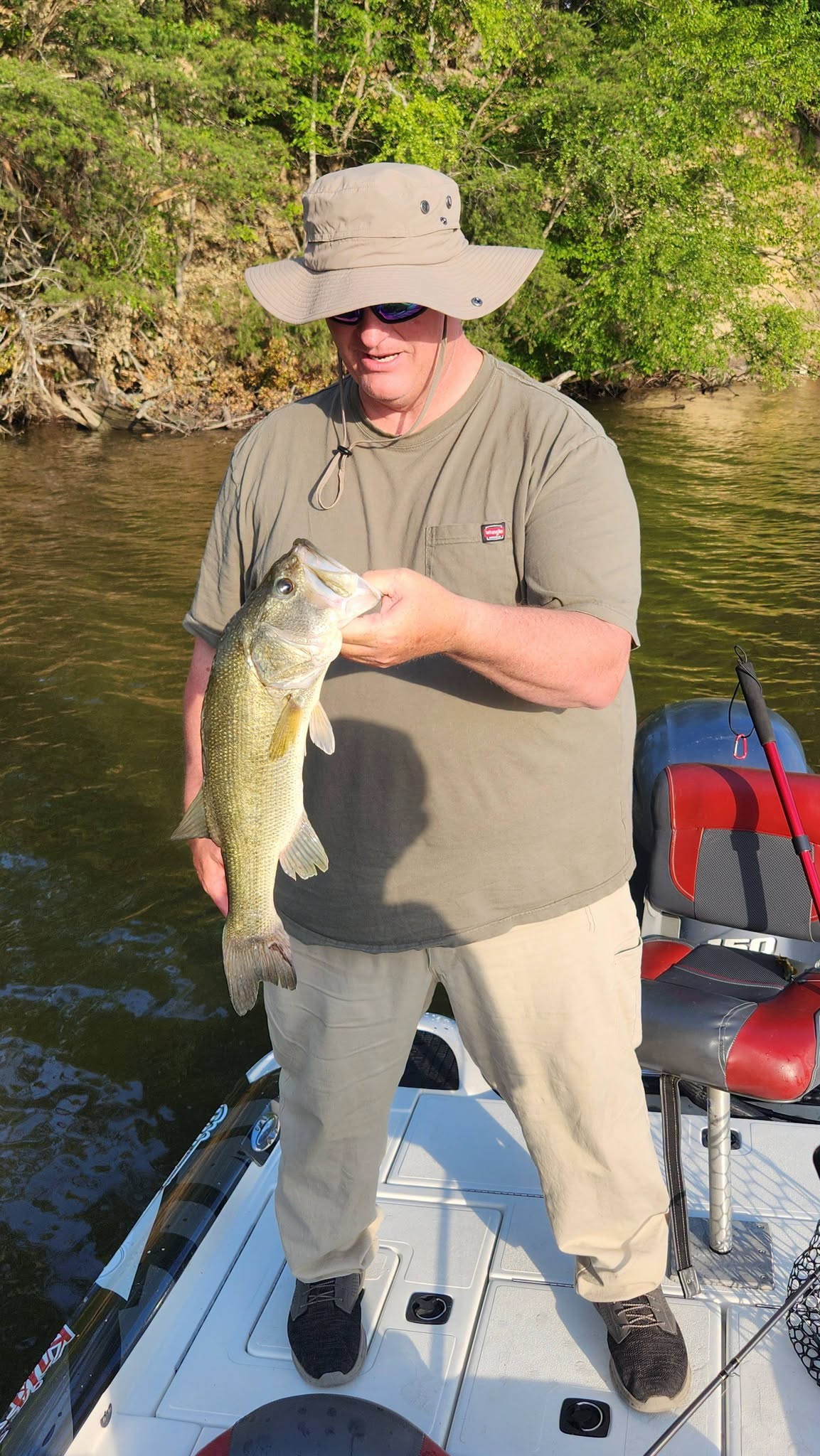 Angler holding caught bass fish on boat in King George VA waterway