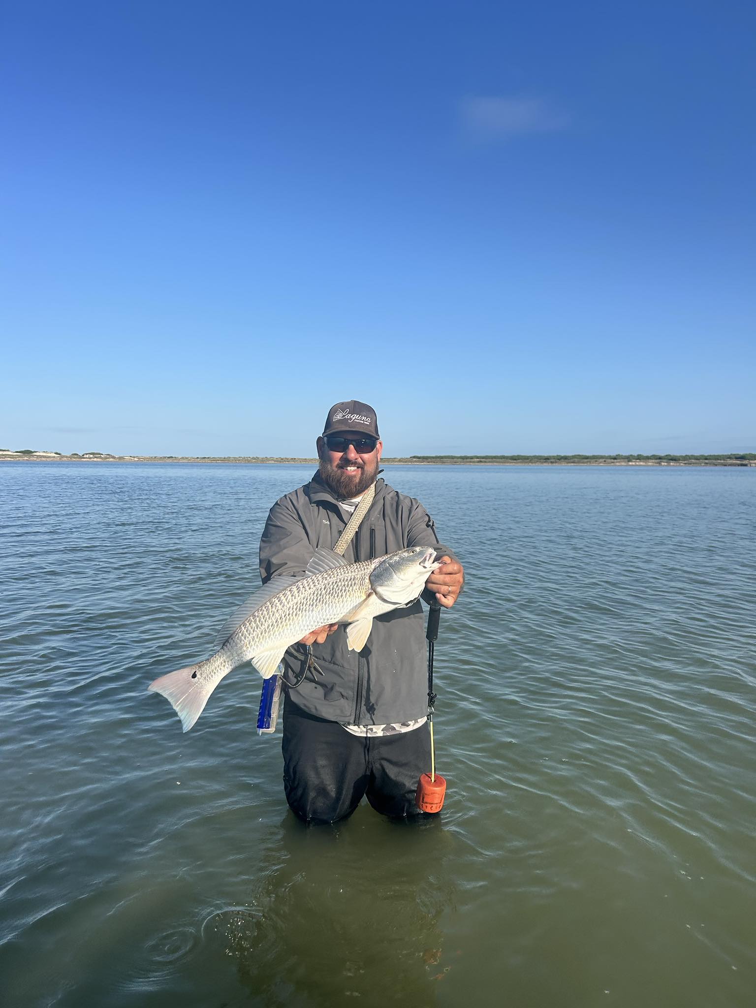 Angler holding caught redfish while wade fishing in Corpus Christi Texas waters