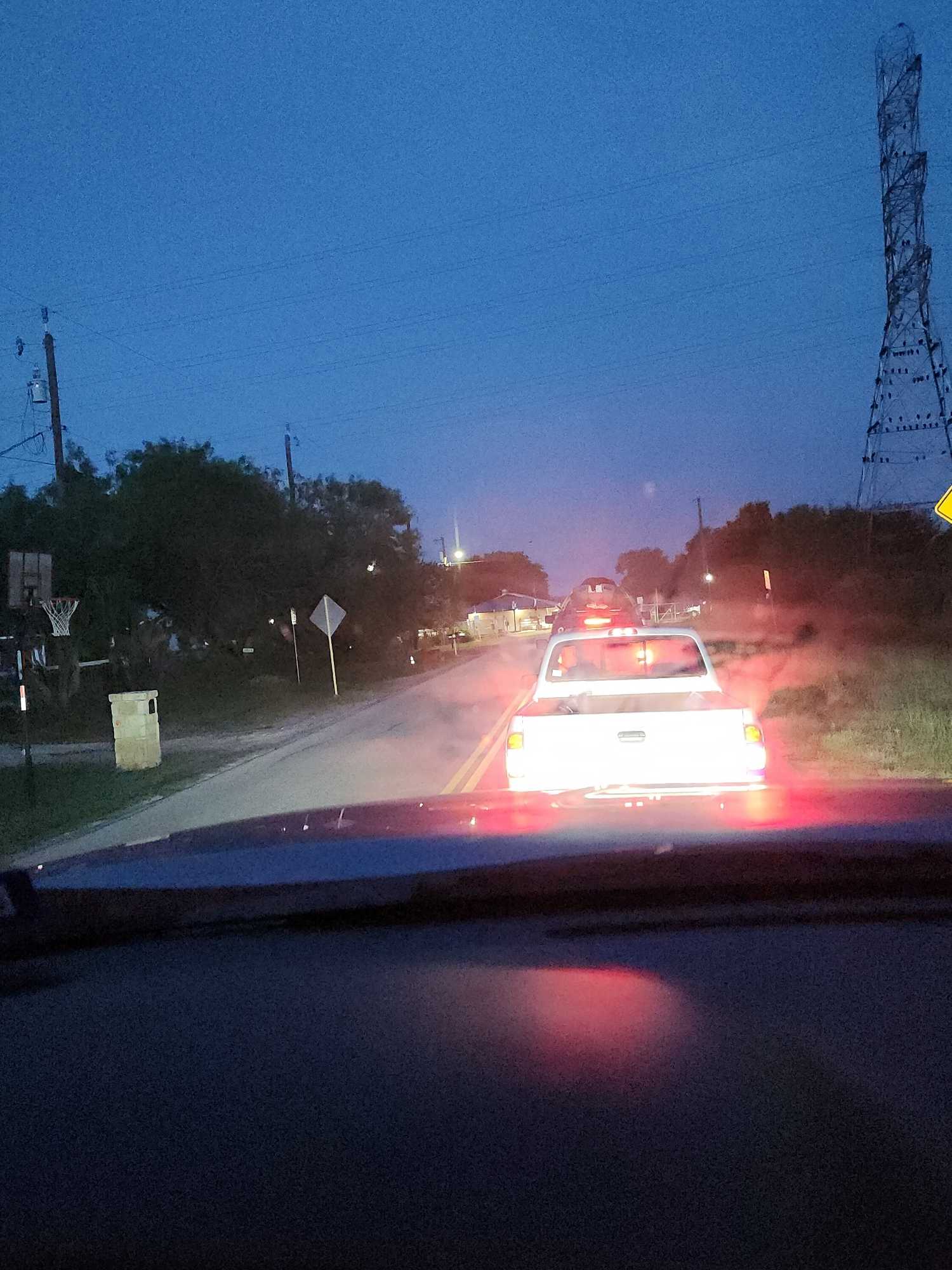 Evening drive on rural road in San Antonio TX with vehicles and transmission tower visible