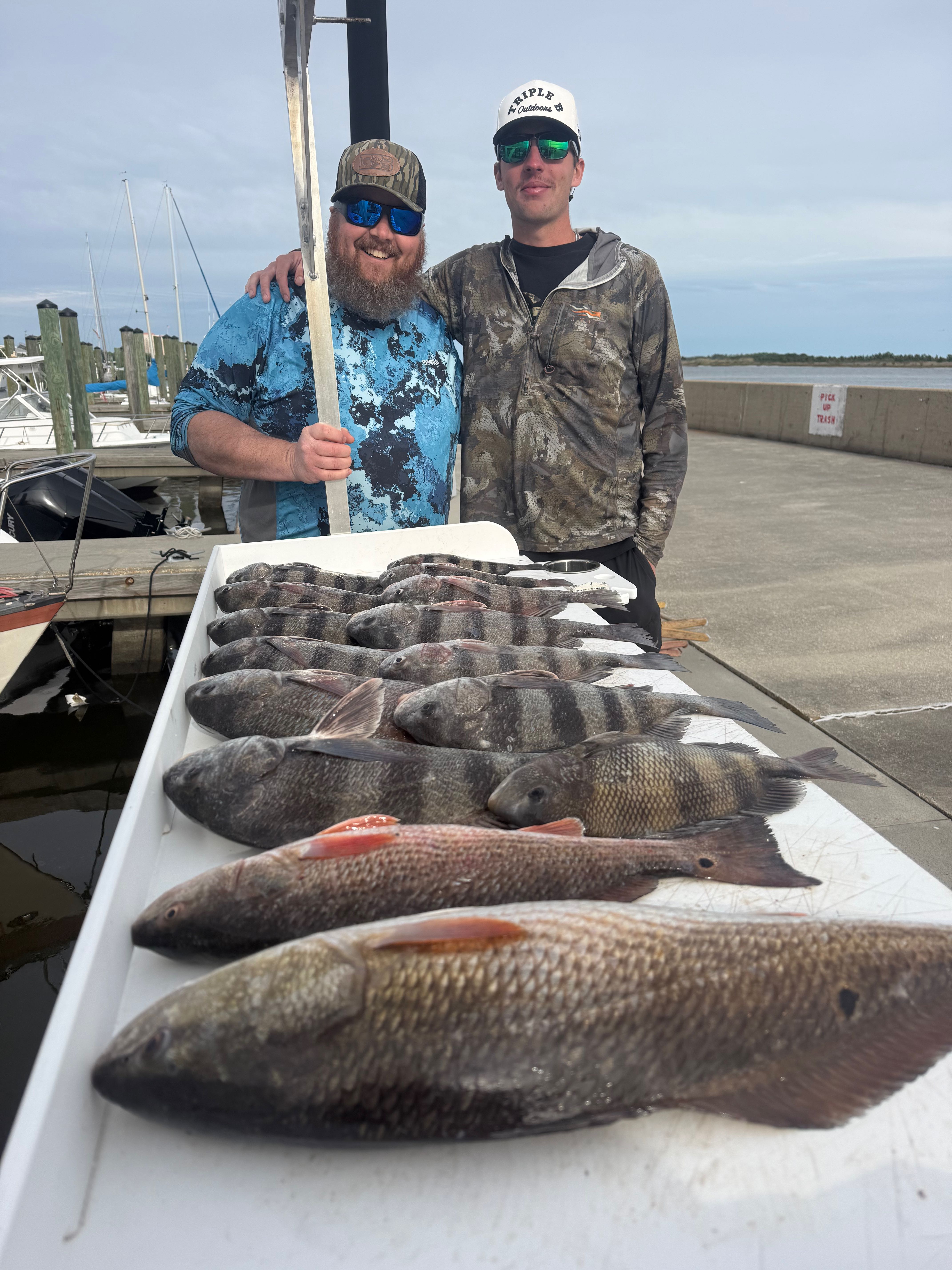 Successful fishing trip in Biloxi MS showing catch of redfish, black drum, and sheepshead laid out on cleaning table at marina dock