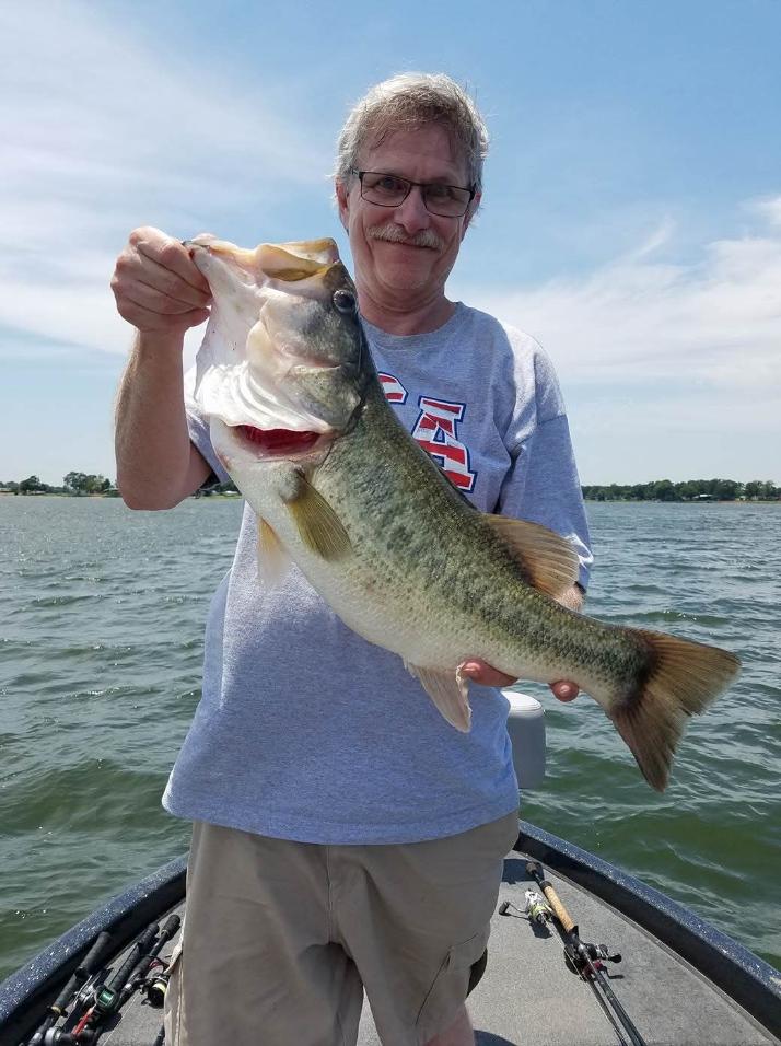 Angler holding large bass fish on boat in Alba TX lake