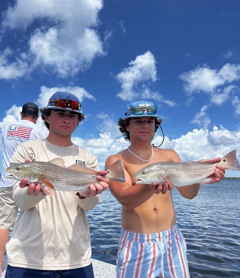 Two anglers displaying freshly caught redfish on fishing charter in Placida FL