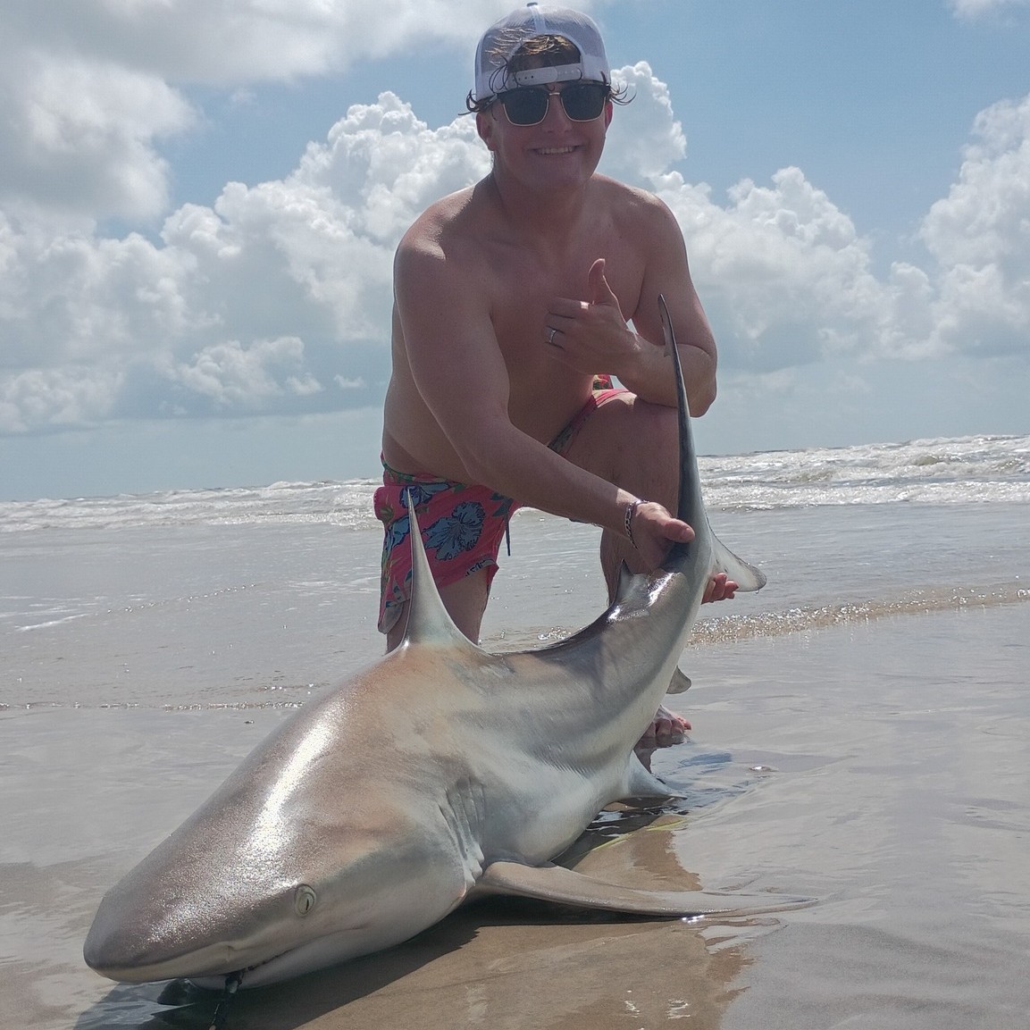 Anglers shark fishing from Galveston beach with surf rods and bait rigs on guided shore trip