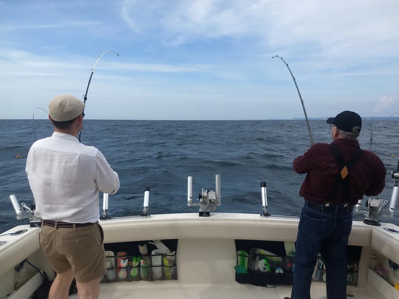 Deep sea fishing from boat deck with bent fishing rods indicating fish on the line in Manistee MI waters