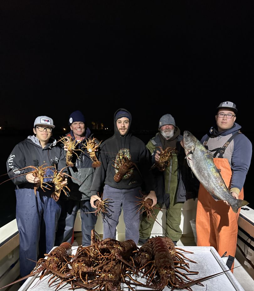 A group of 5 people fishing at Huntington Beach