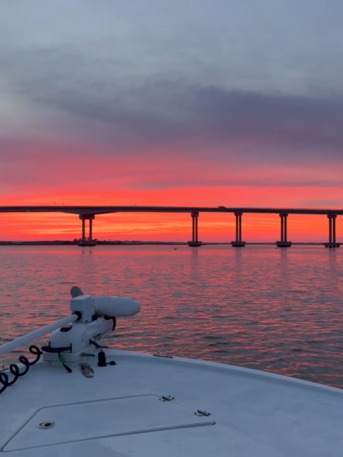 Fishing boat on calm water at sunset with bridge in background in Morehead City NC