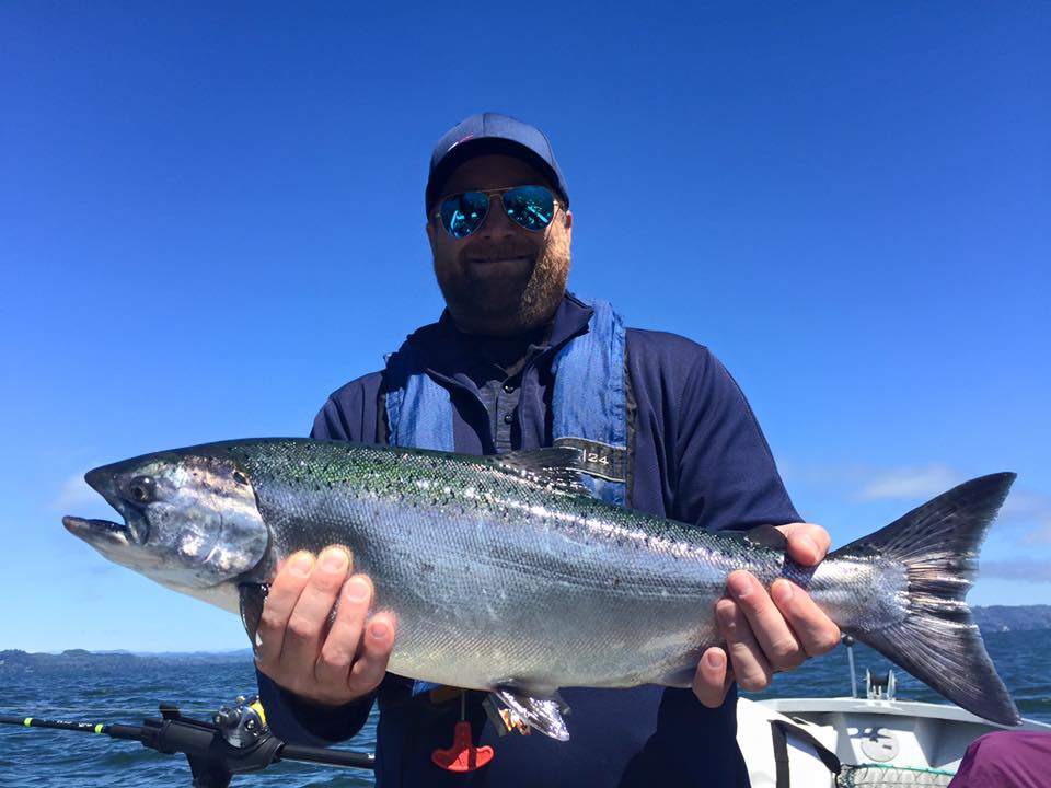 A photograph of a fisherman holding a large rainbow trout in Portland, Oregon.