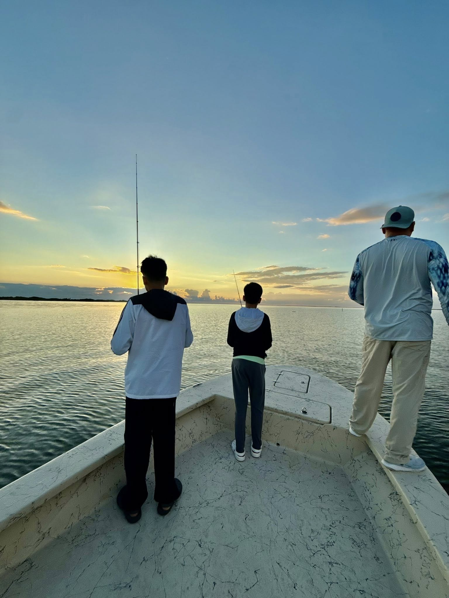 Fishing boat on calm water at sunset in Riviera Texas with fishing rods visible