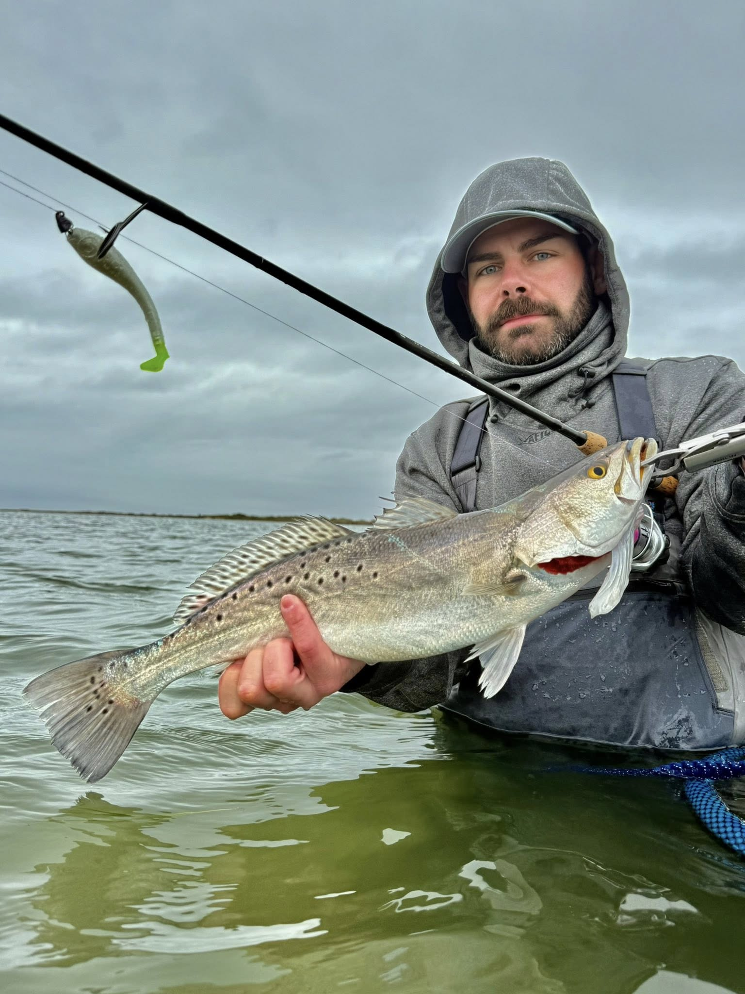 Angler holding freshly caught speckled trout while wade fishing in Riviera Texas coastal waters