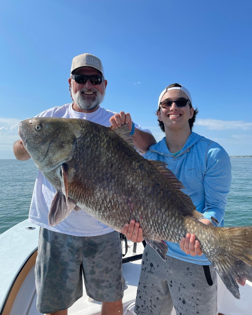 Angler holding a large black drum fish caught in SC